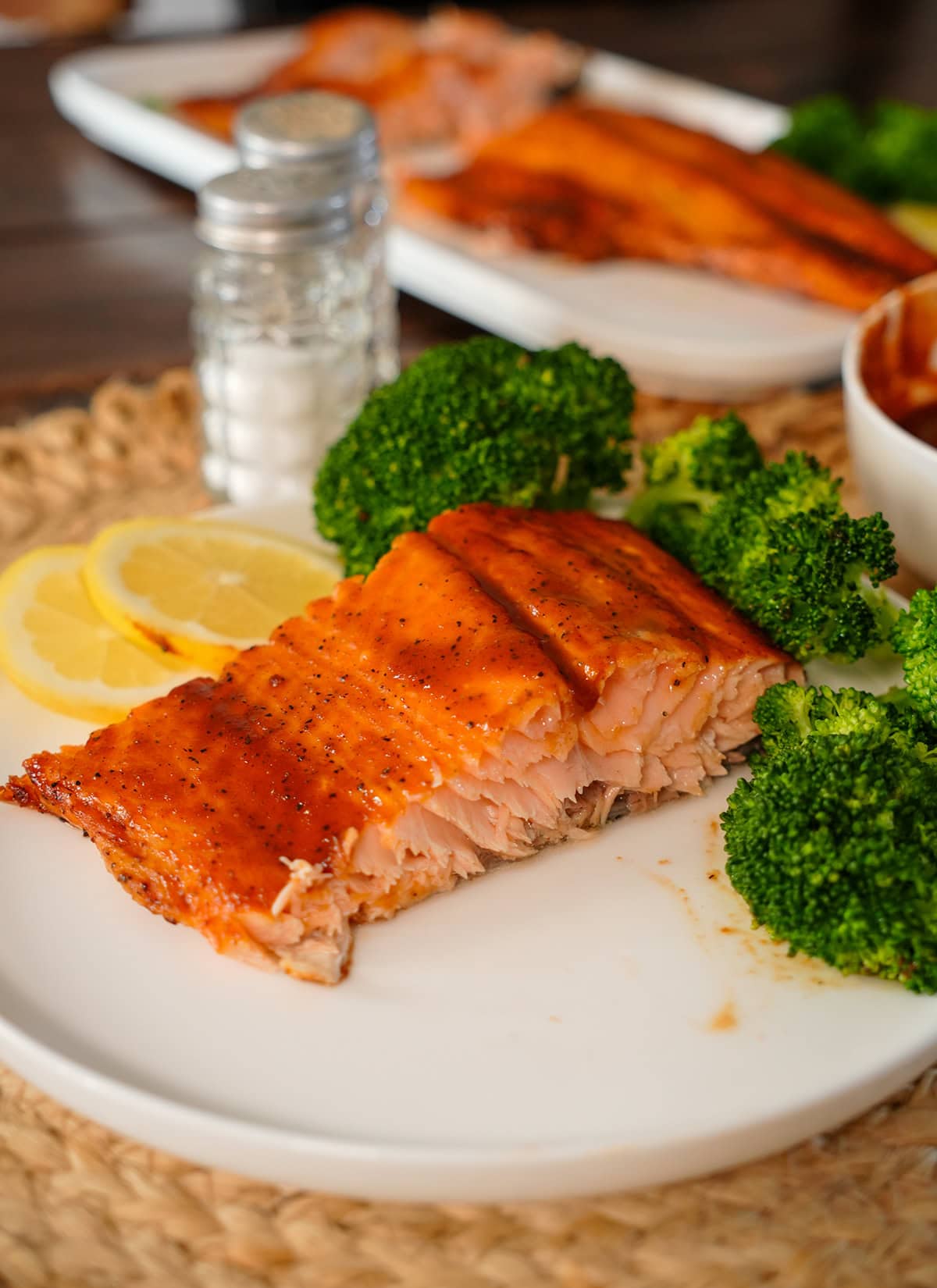 A plated piece of Salmon with lemon and broccoli.