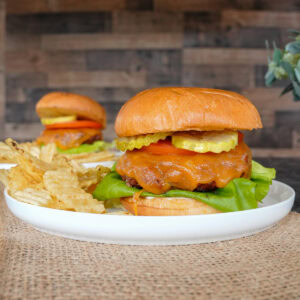 2 Butter Burgers on plates with potato chips.