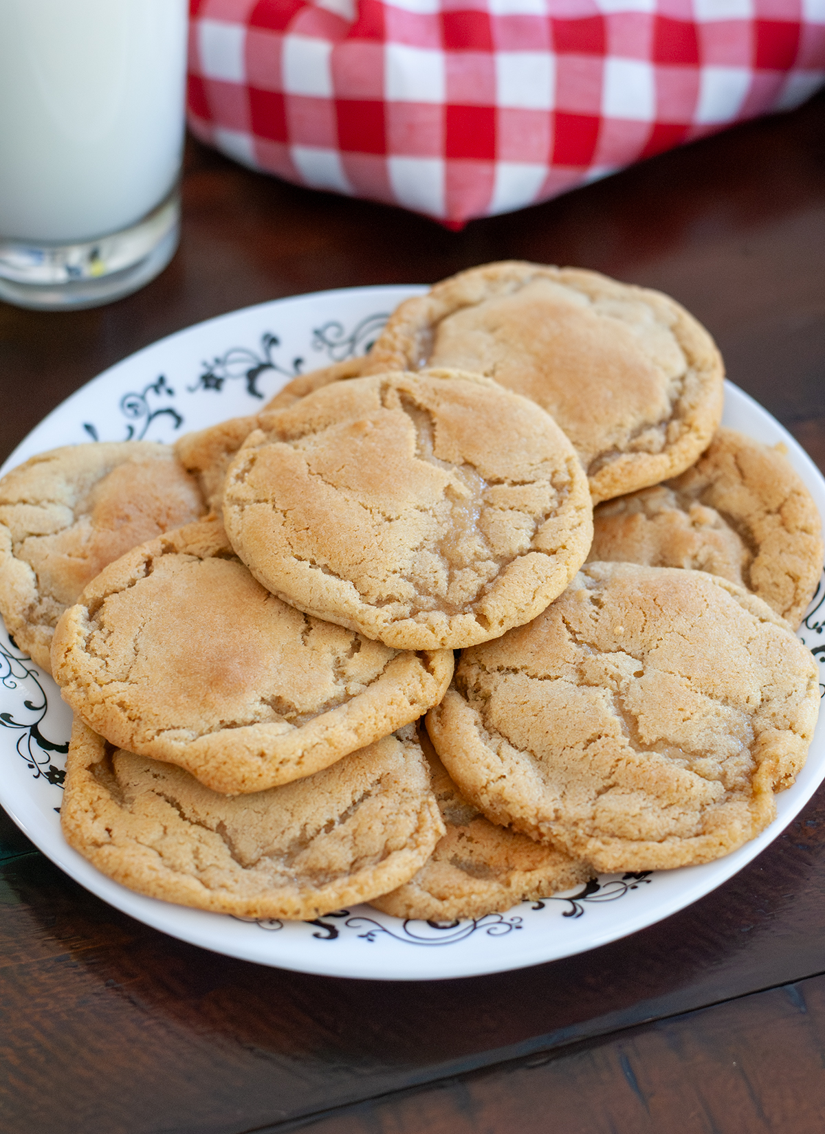 A plate of golden, chewy Chocolate Chipless Cookies with a glass of milk. 