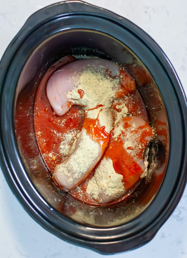 Top view of chicken, ranch and hot sauce in crock pot. 