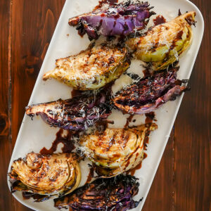 Grilled cabbage on a white plate with balsamic vinegar.