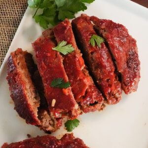 grilled meatloaf sliced into pieces on a plate with parsley.