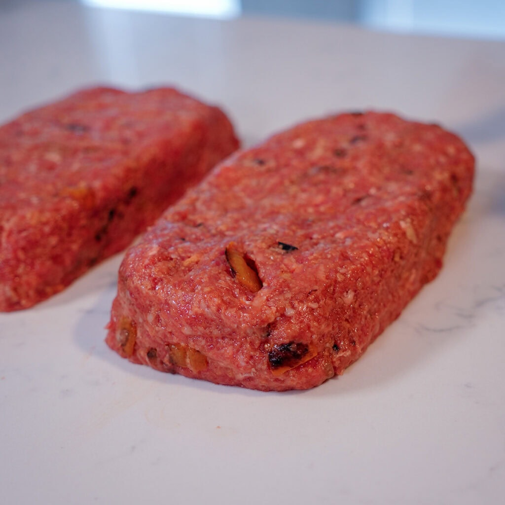 uncooked meatloaf loaves on a countertop.