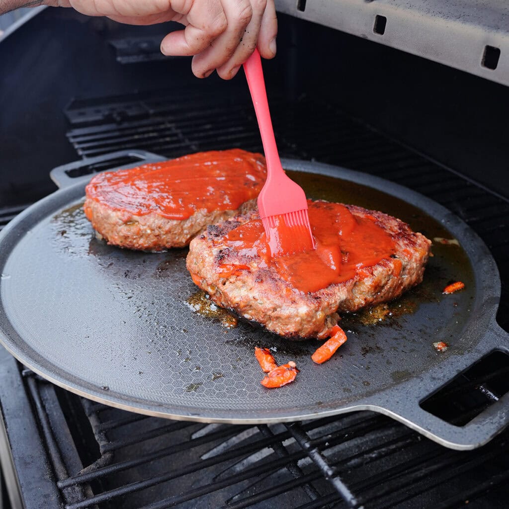 grilled meatloaf being basted with ketchup.