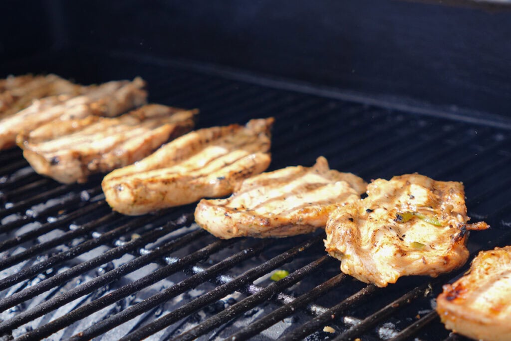 Chicken grilling on grill racks.