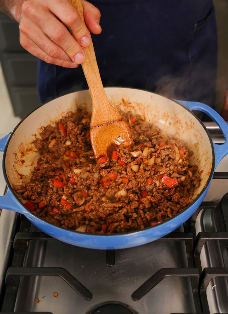 A skillet of cooked ground beef, peppers and onions.