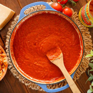 Tomato sauce in a blue dish with san marzanos tomatoes.
