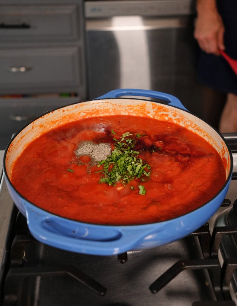 Fresh basil on top of tomato sauce on the stove. 