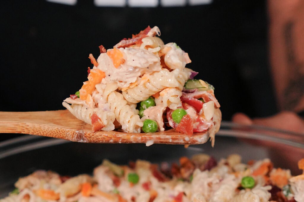 A scoop of pasta salad showing chopped vegetables and creamy ranch.