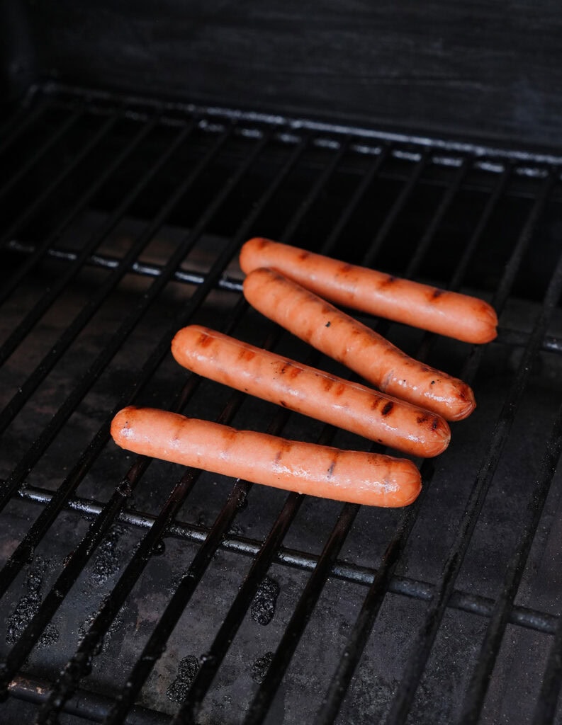 Hot dogs on a grill with grill marks. 