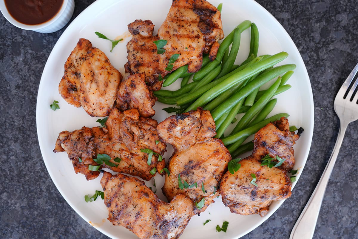 A platter of grilled thighs with some chopped parsley. 