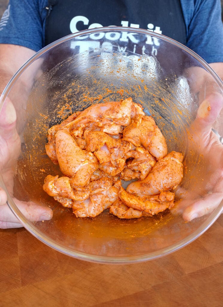 seasoned and marinaded chicken thighs in a bowl.