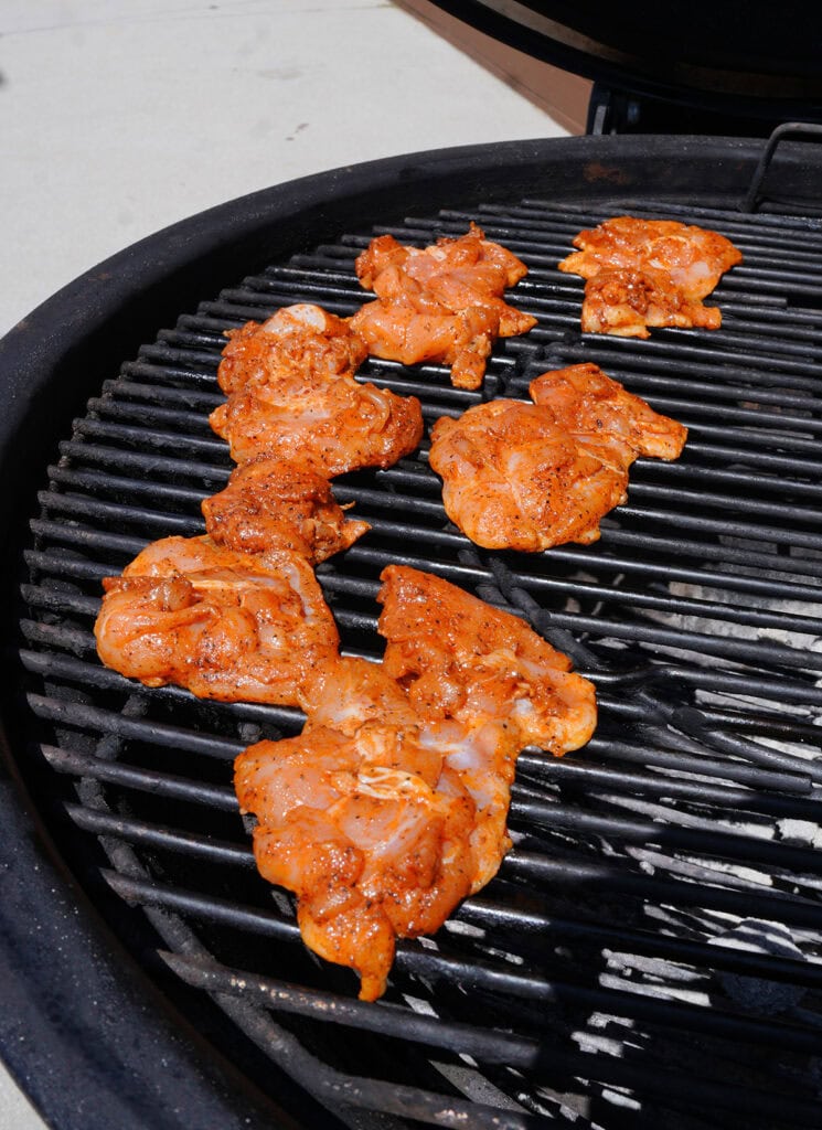 chicken thighs grilling over charcoal.