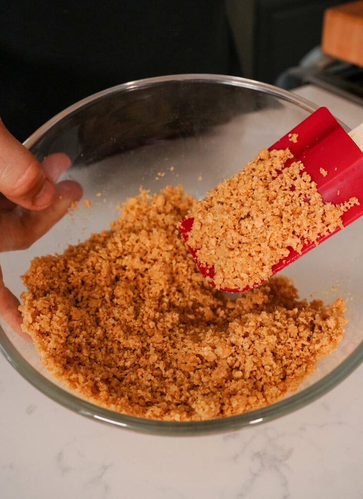 A bowl of crushed graham crackers mixed with butter and sugar. 