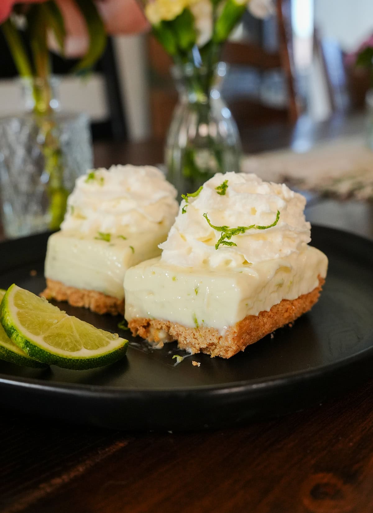 Key Lime Bars on a plate garnished with whipped cream and lime zest. 
