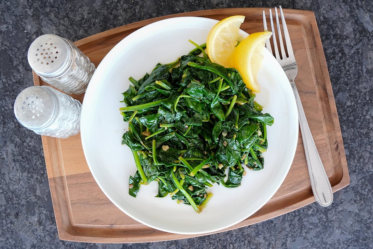 Spinach on a serving tray with salt and pepper.