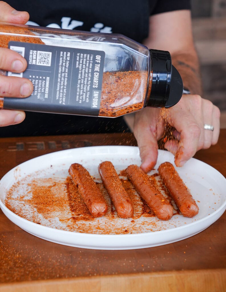 Hot dogs being seasoning with a pork rub.