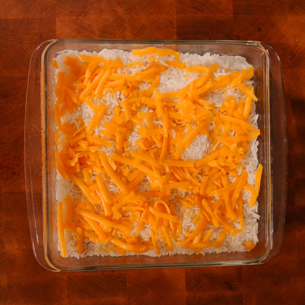 Cheese on top of rice in a casserole dish.