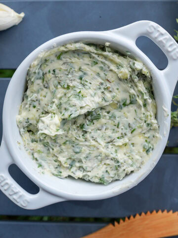 Garlic herb butter in a staub dish with a knife.