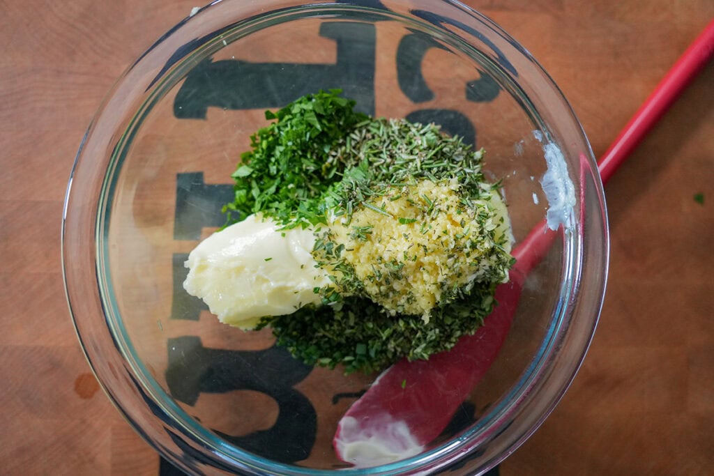 chopped herbs and butter in a glass mixing bowl.