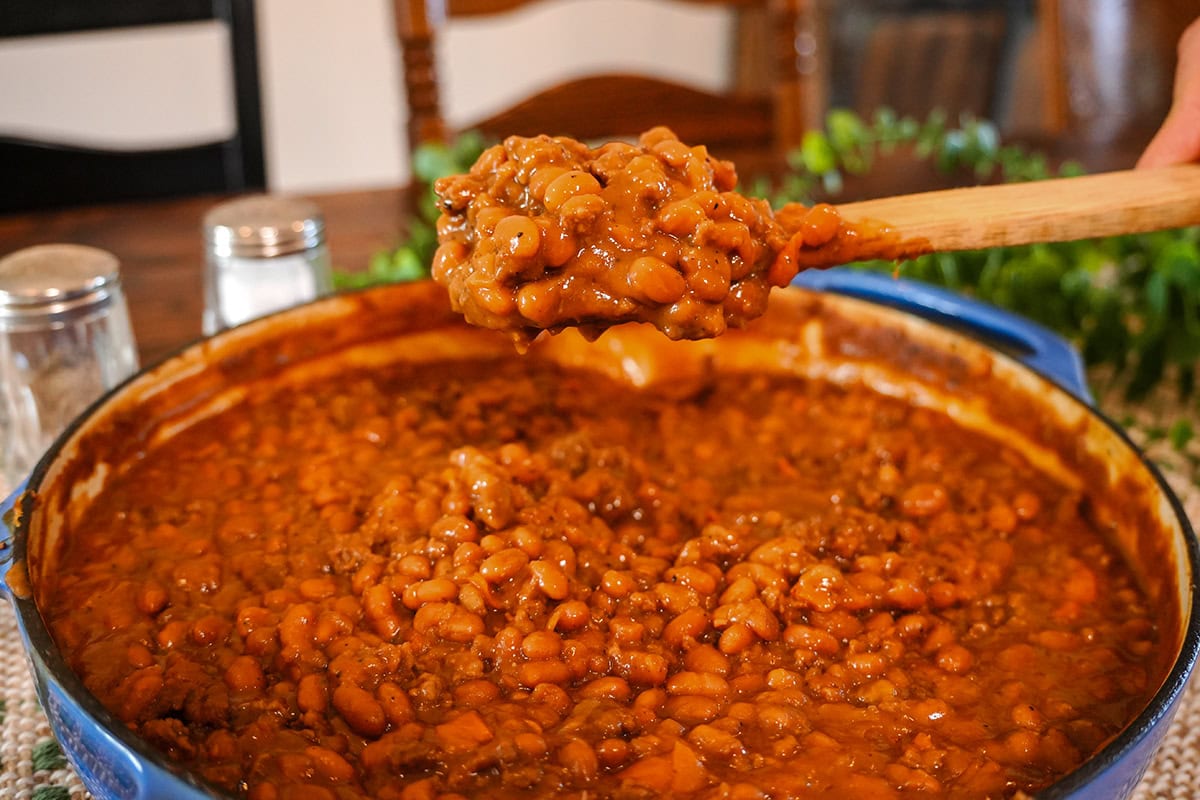 a wooden spoonful of baked beans and hamburger meat.