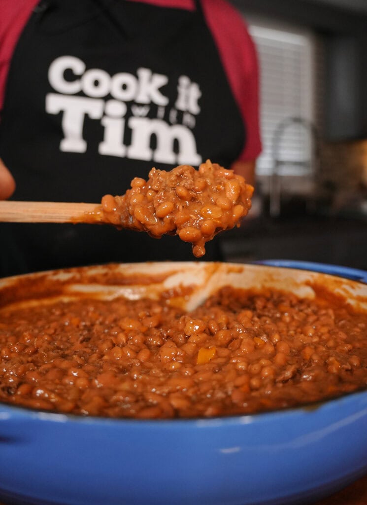 a spoonful of baked beans and ground beef over a skillet.