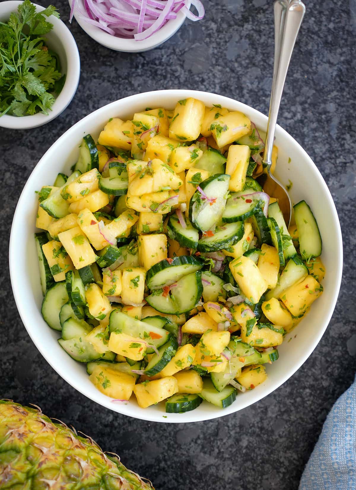 Cucumber and pineapple salad in a bowl with red onions and chili flakes.