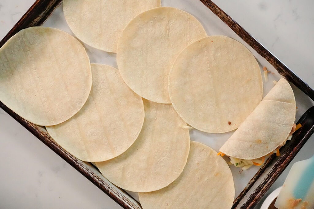 a folded corn tortilla taco filled with cheese, beans and beef.