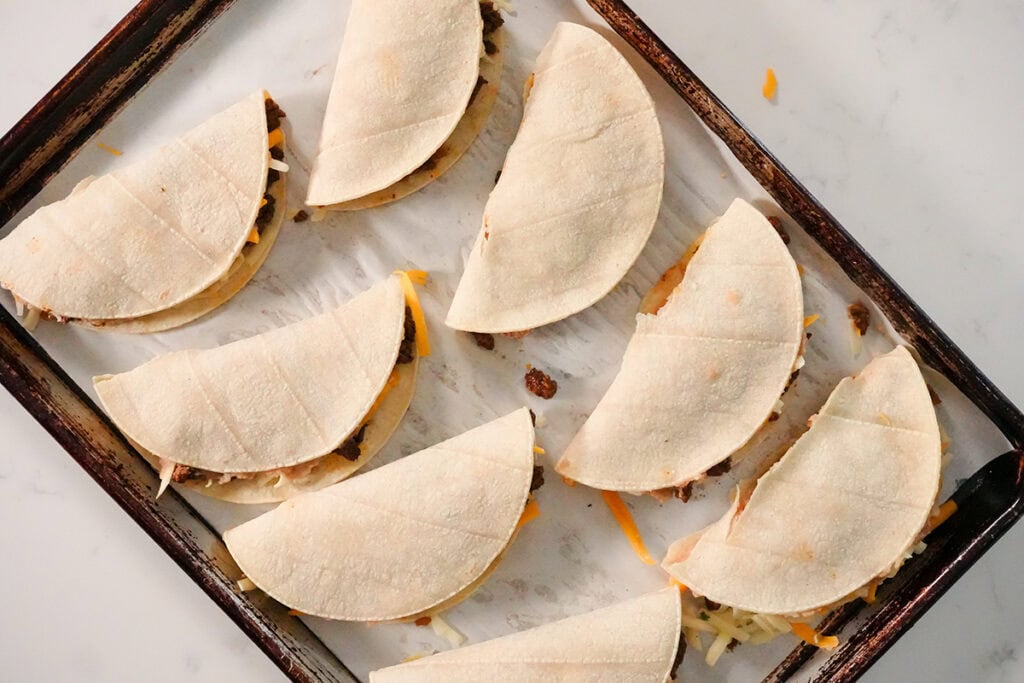 folded tacos on a baking sheet.