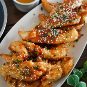 honey garlic chicken fingers with sesame seeds and chives.