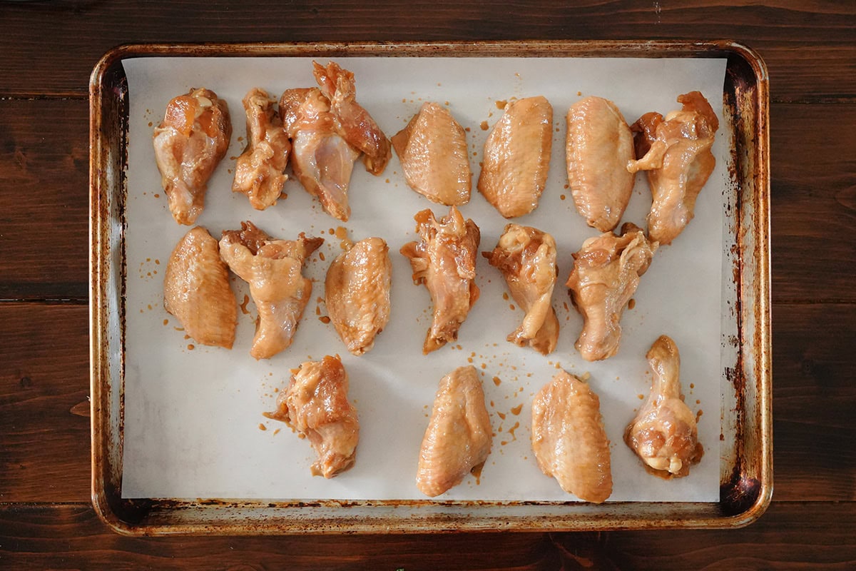 chicken wings laid in a single layer on a baking sheet.