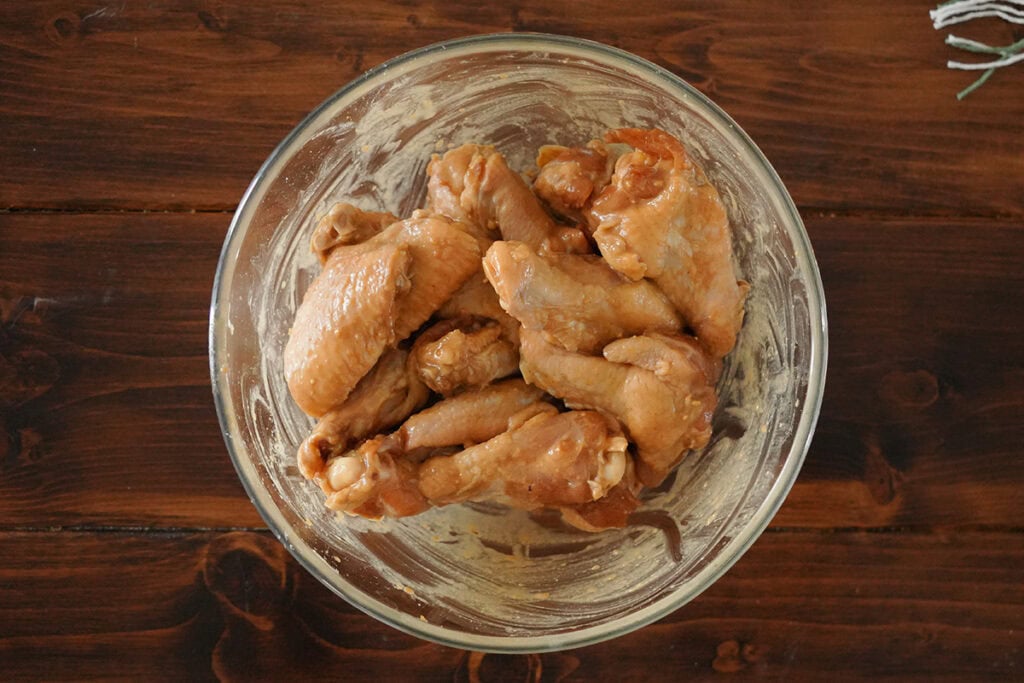 chicken wings mixed with seasonings in a bowl.