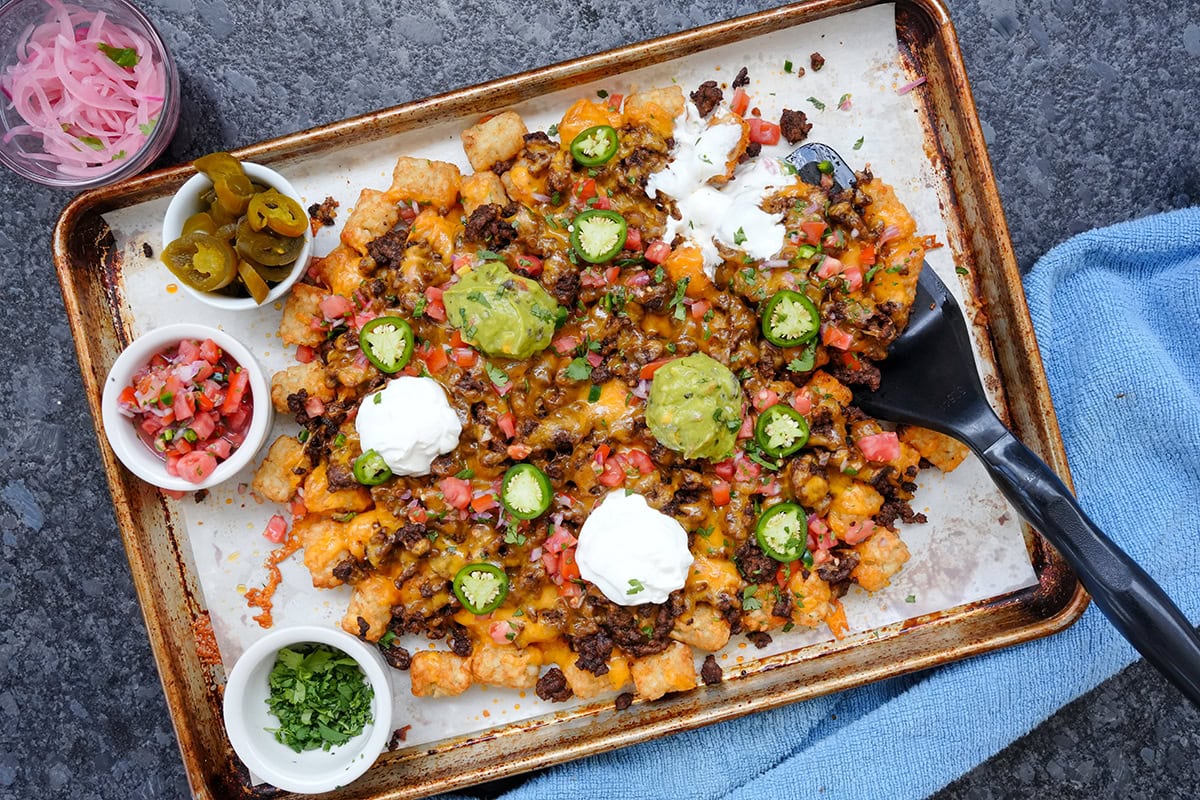 totchos on a baking sheet covered with Mexican toppings.