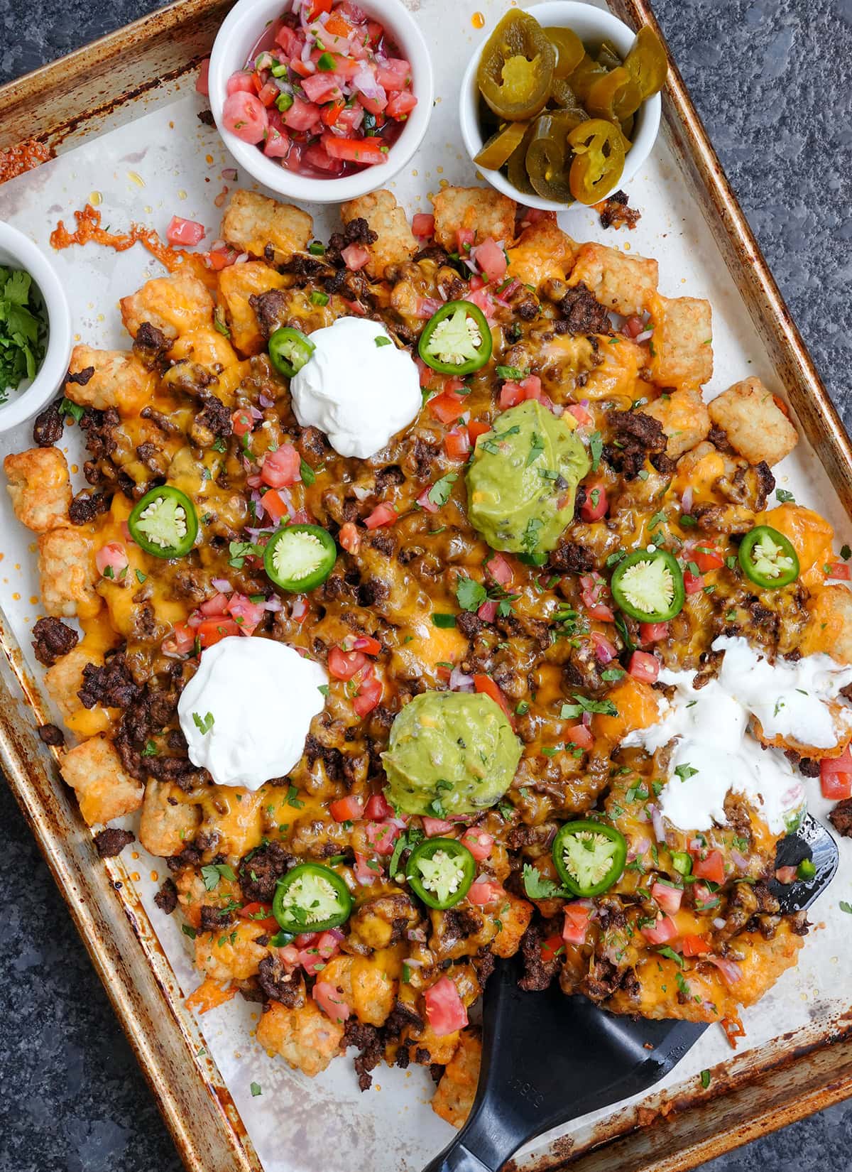 Tater tots loaded with nacho toppings and pico de Gallo and sour cream.