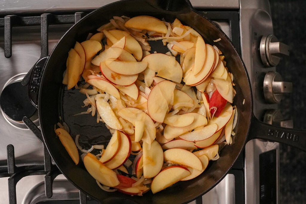 apples and onions cooking in a skillet.