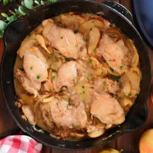 Apples and chicken in a skillet with broth and onions.