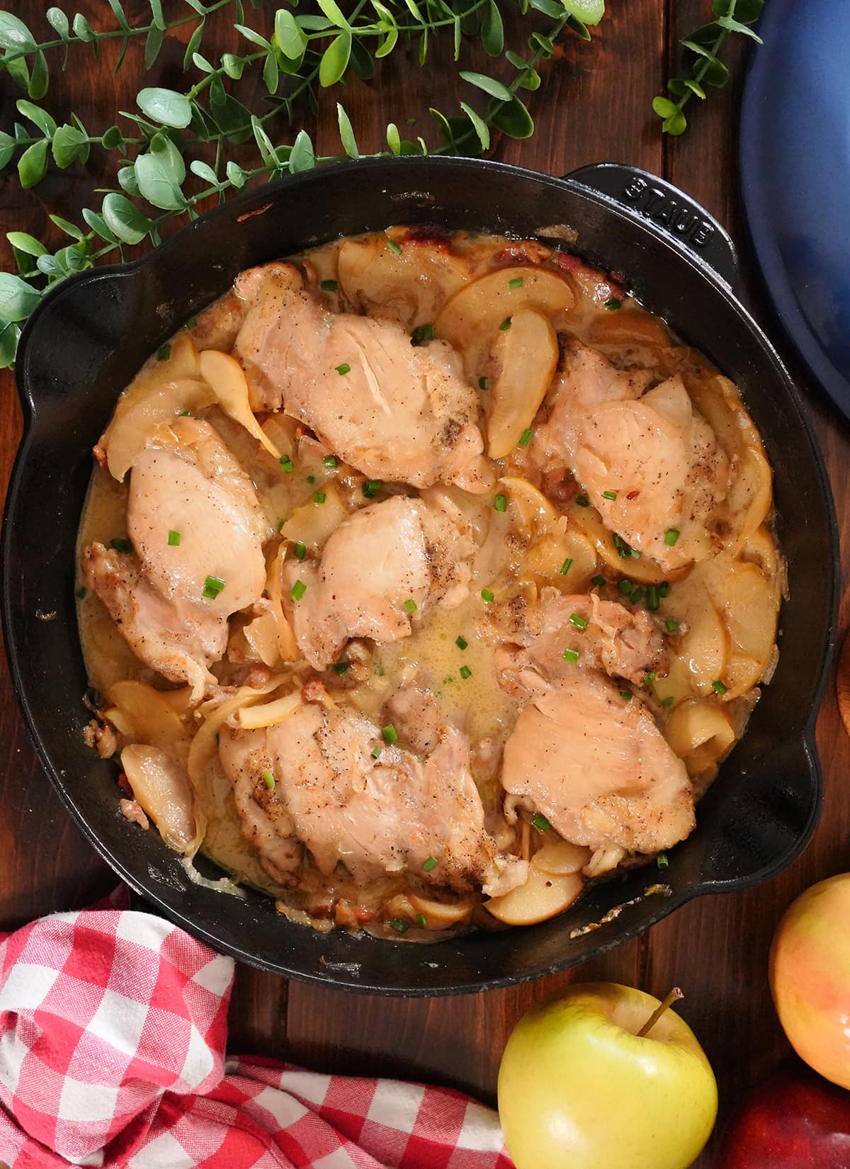 Apples and Chicken thighs in a skillet topped with chives and onions.