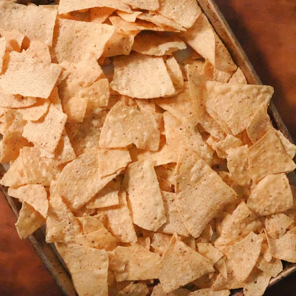 A layer of tortilla chips on a baking sheet.