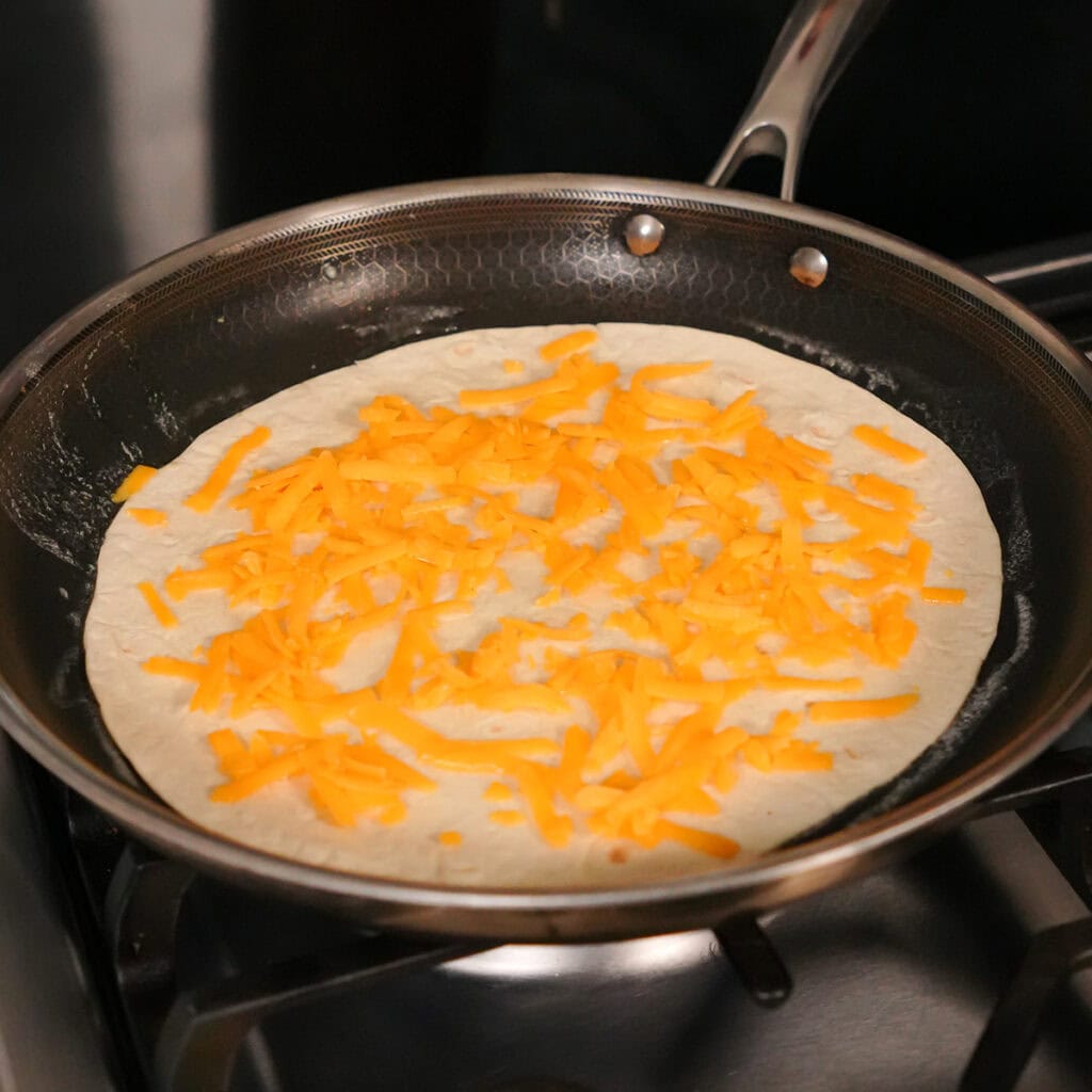 a tortilla with cheese in a skillet.