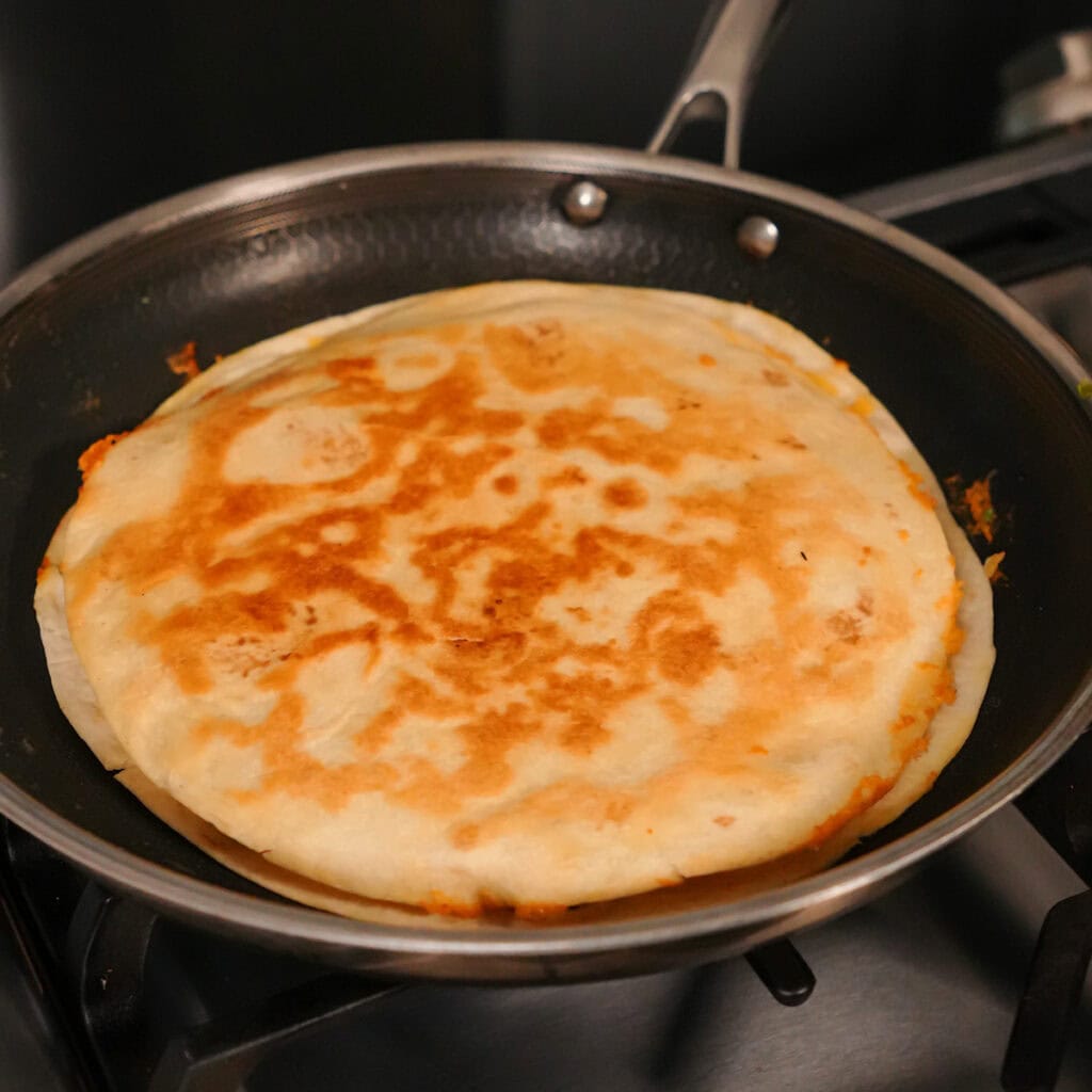 a quesadilla cooking in a skillet.
