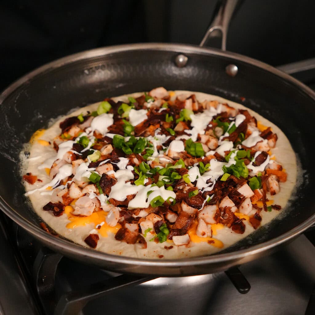 chicken bacon and ranch on a tortilla in a skillet.