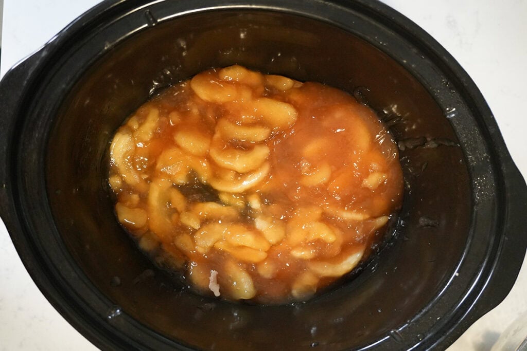 canned apples in the bottom of a slow cooker.