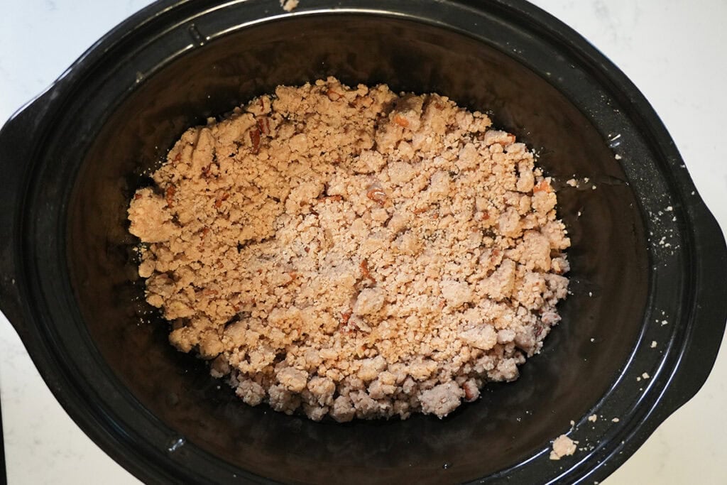 cake mixture on top of apples in a crockpot.