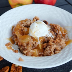 Crock pot apple dump cake in a bowl with ice cream.