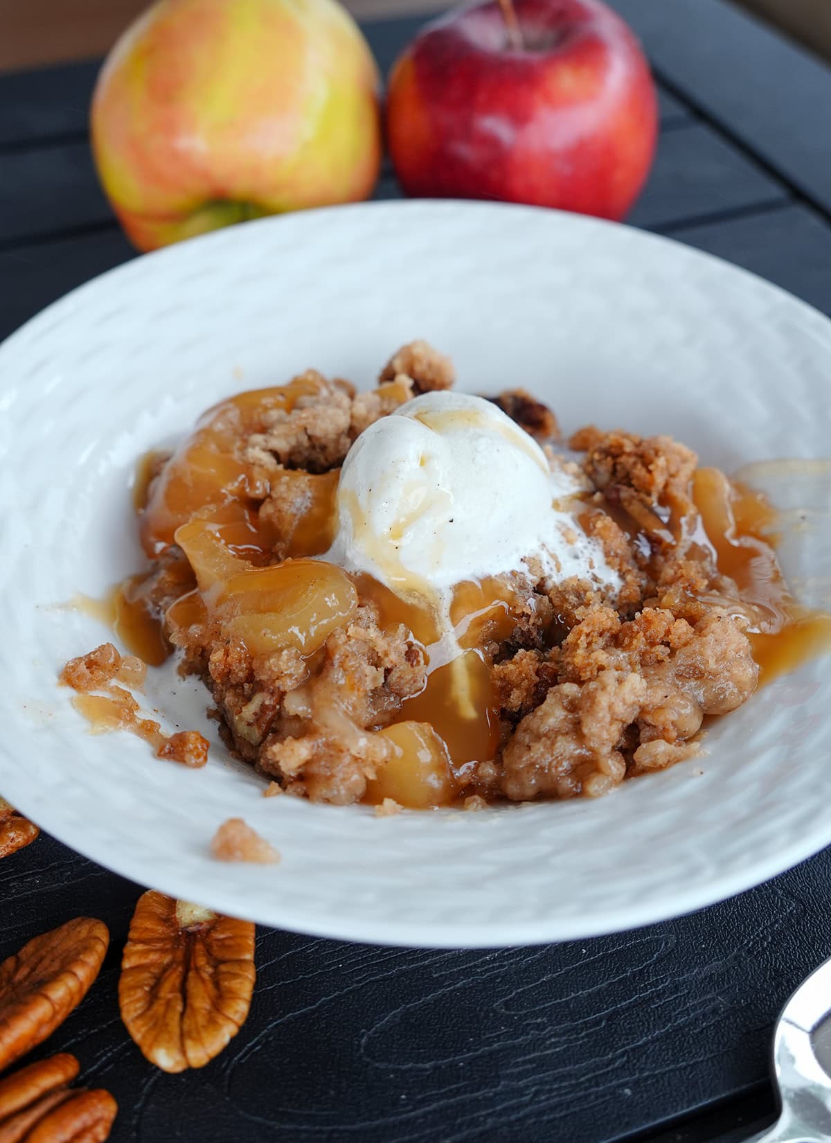 crock pot apple dump cake in a bowl with ice cream and caramel.