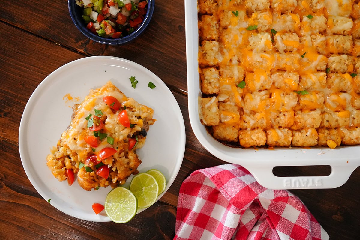 A slice of casserole next to a casserole dish with salsa.