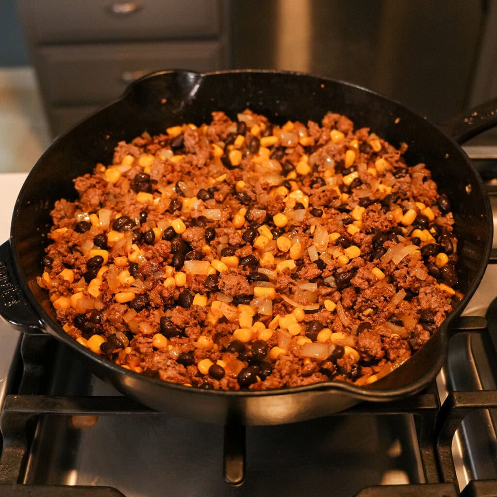 corn, beans and beef cooking in a skillet.