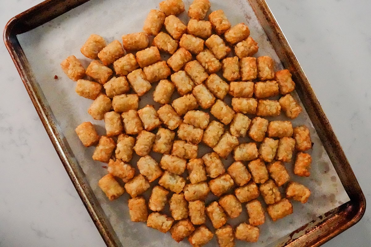 tater tots spread out on a baking sheet.
