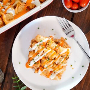 tater tots and buffalo chicken in a casserole with ranch drizzle.