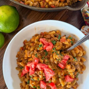 Mac and cheese with taco flavors served with lime and tomatoes.